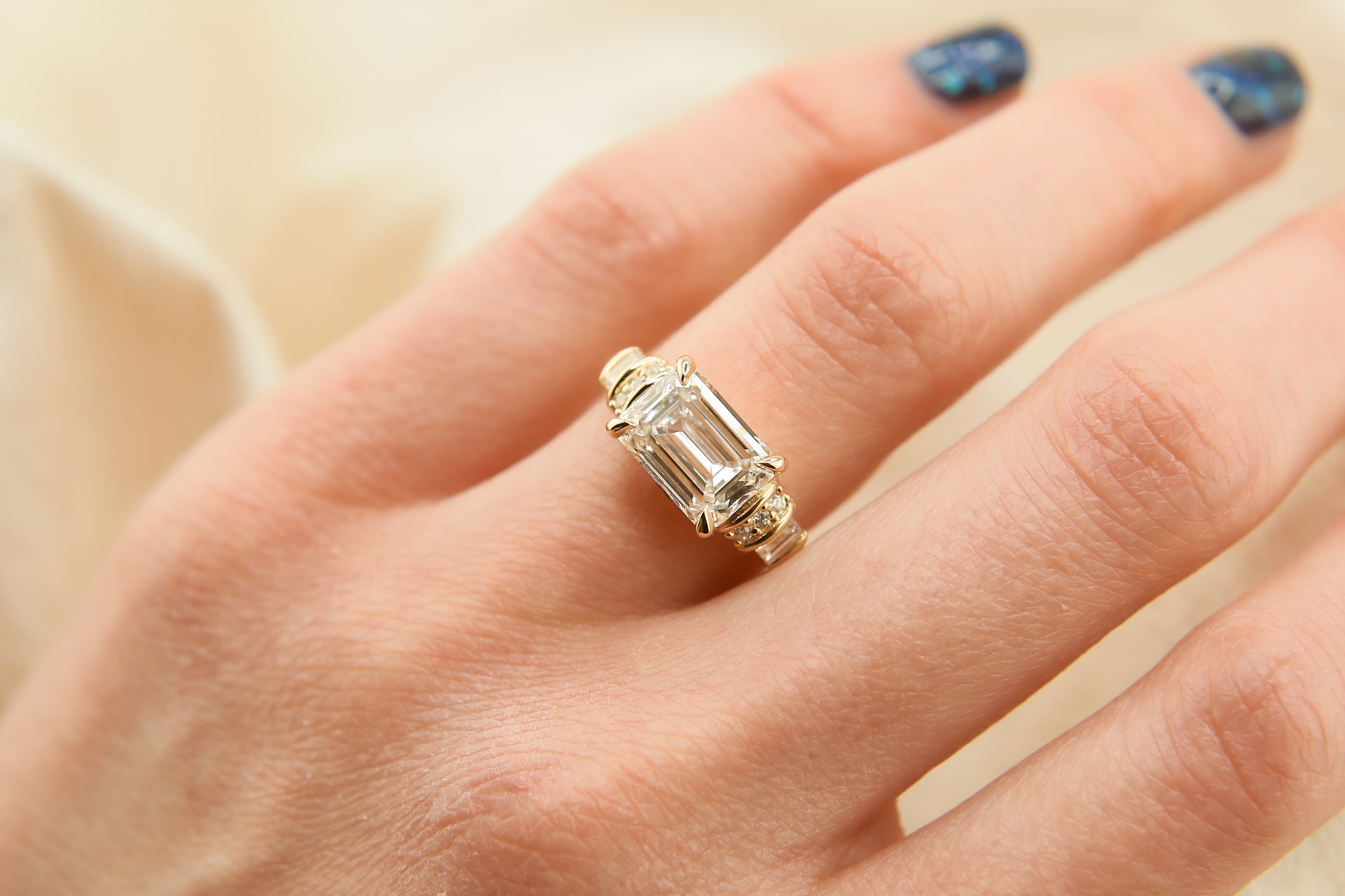 Gold ring with a large diamond on a hand against a neutral background