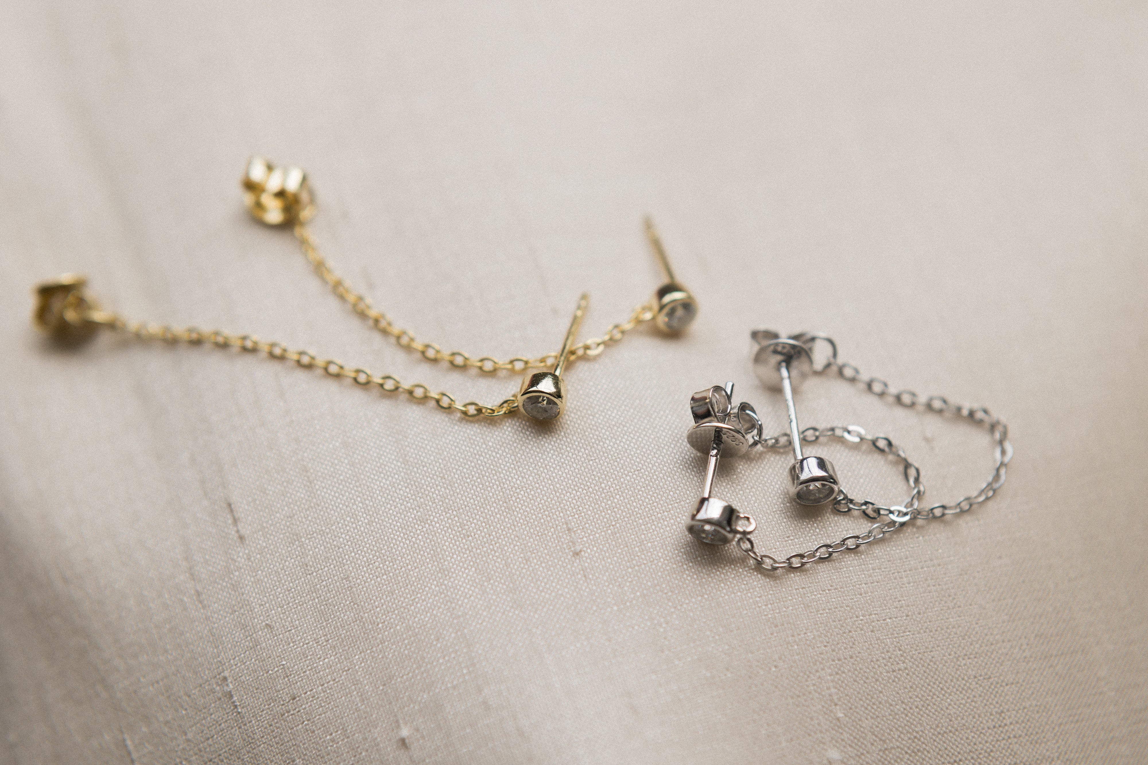 White gold and yellow gold filled moissanite studs with a chain that connects from front to back. Sold by cival in bayview Milwaukee wisconsin