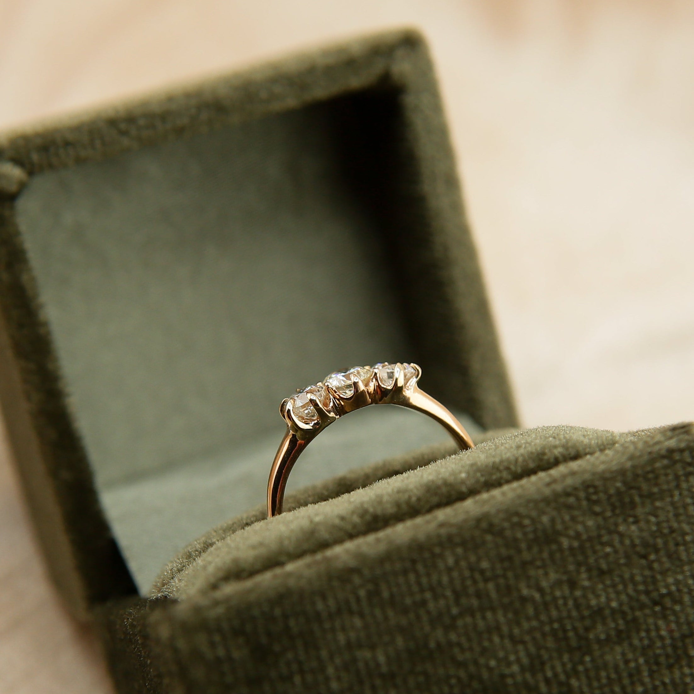 Gold ring in a green velvet box on a soft beige background