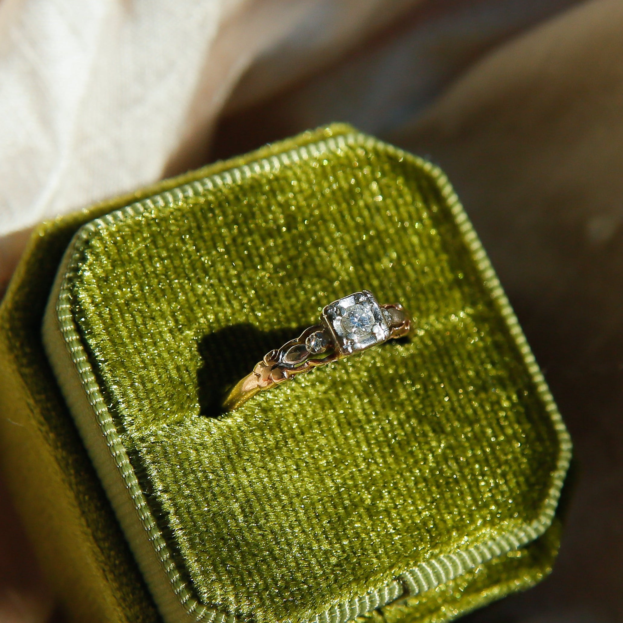 Diamond ring in a green velvet box on beige fabric