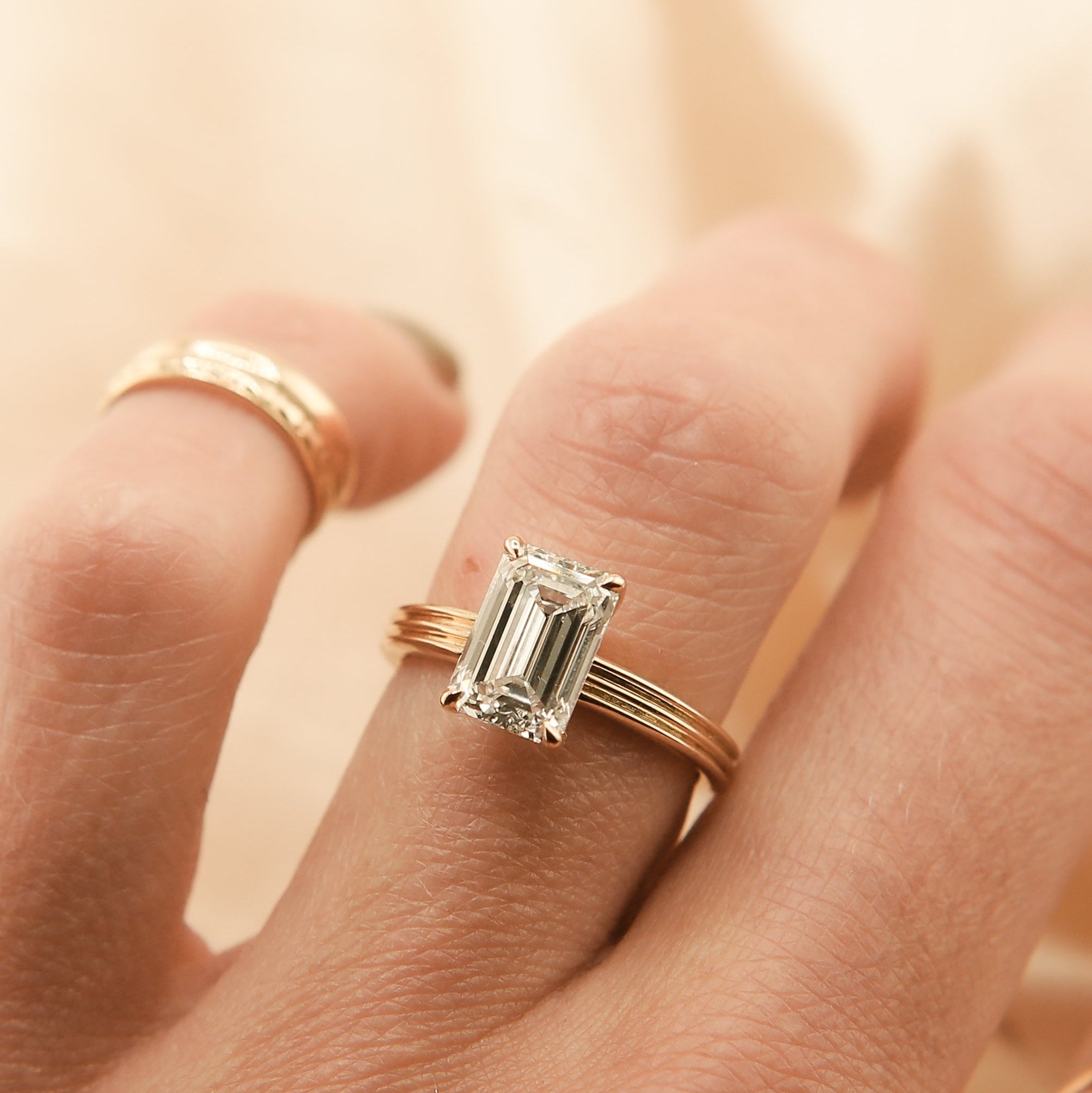 gold engament ring with a diamond on a hand against a soft background