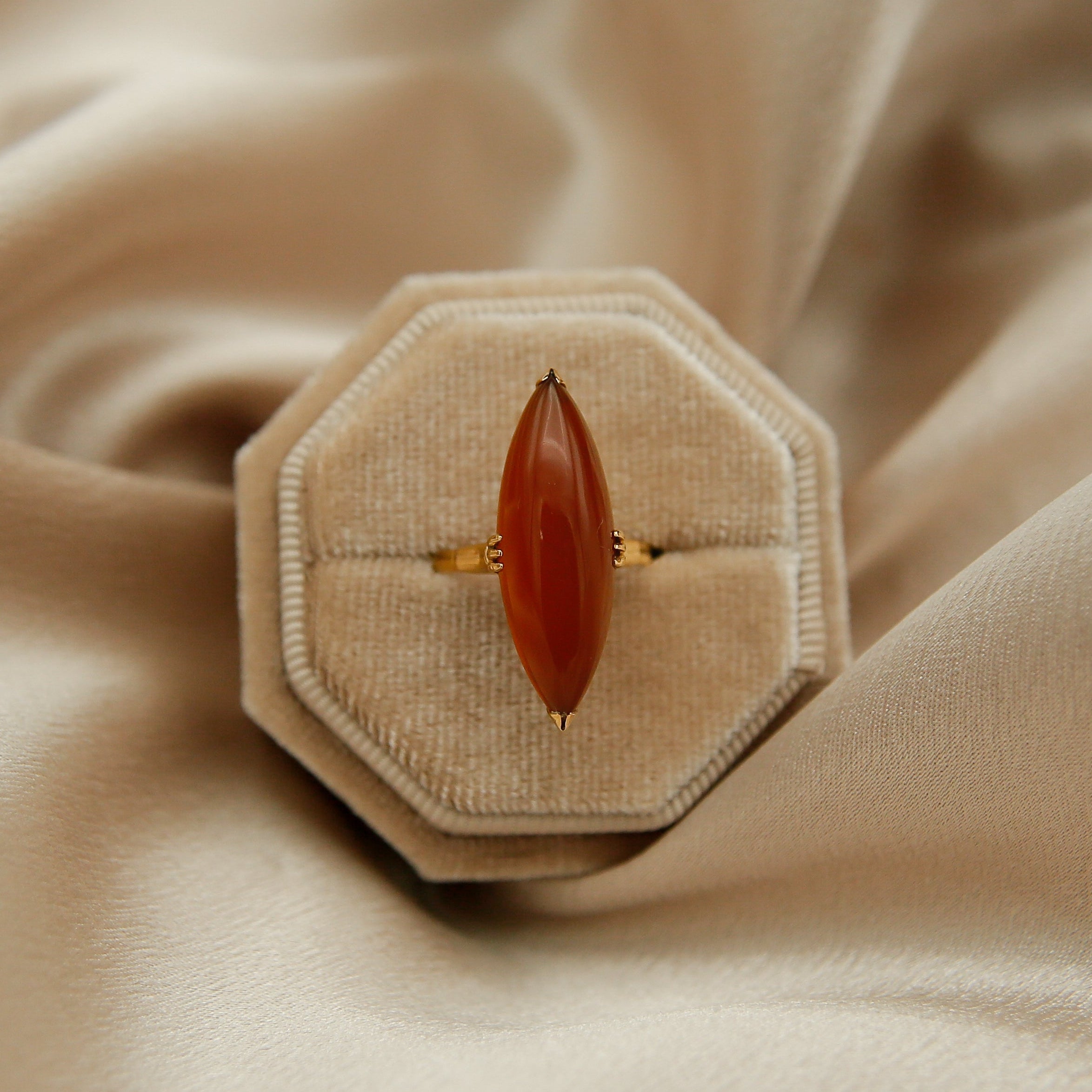 Ring with a red stone in an octagonal box on beige fabric