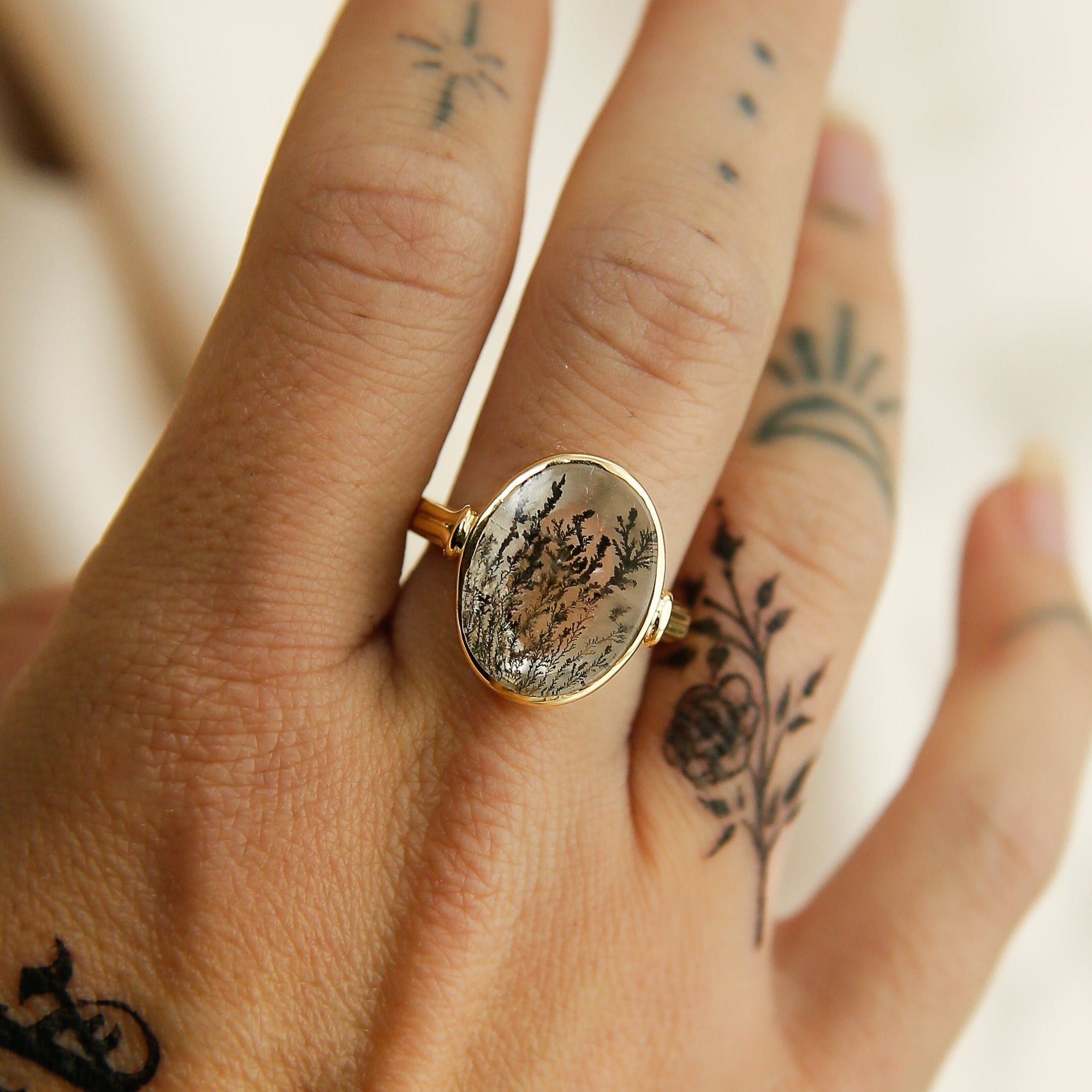 Gold ring with a stone on a hand with tattoos