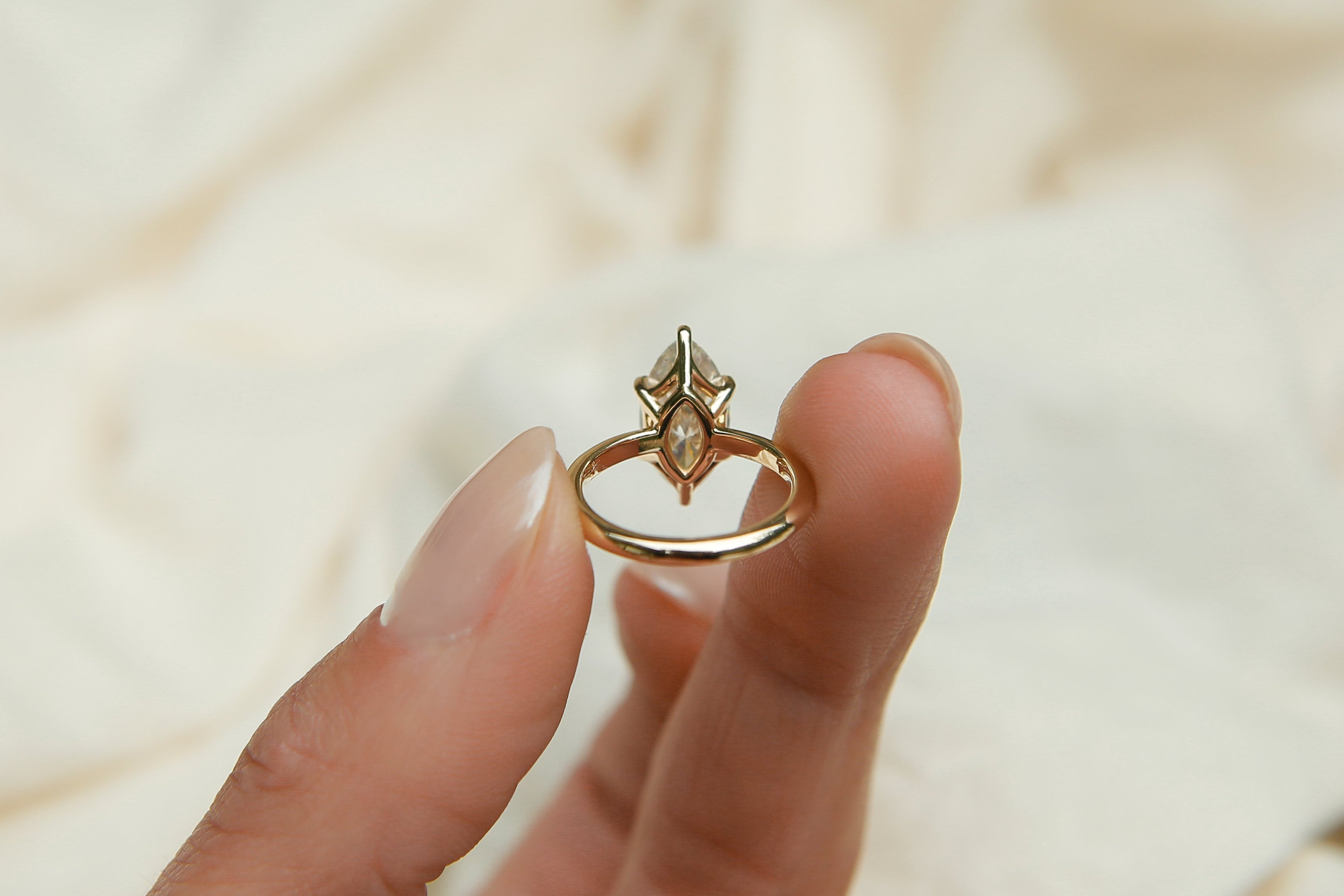 Gold ring with a diamond on a beige fabric background