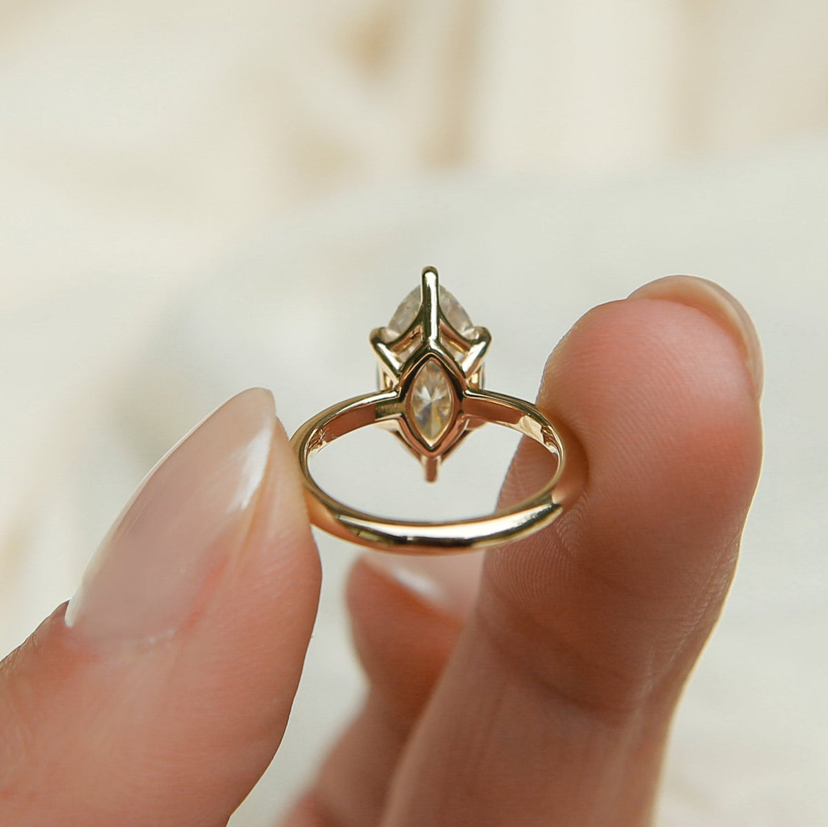 Gold ring with a diamond on a beige fabric background