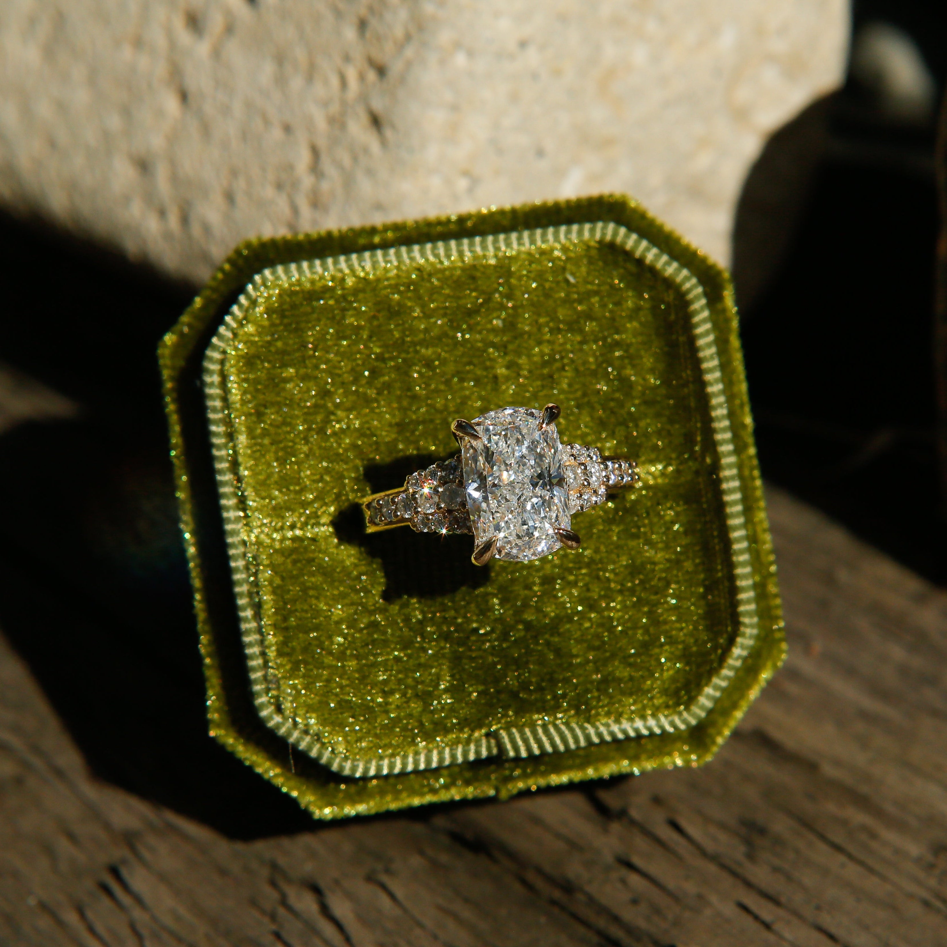 Diamond ring in a green velvet box on a wooden surface