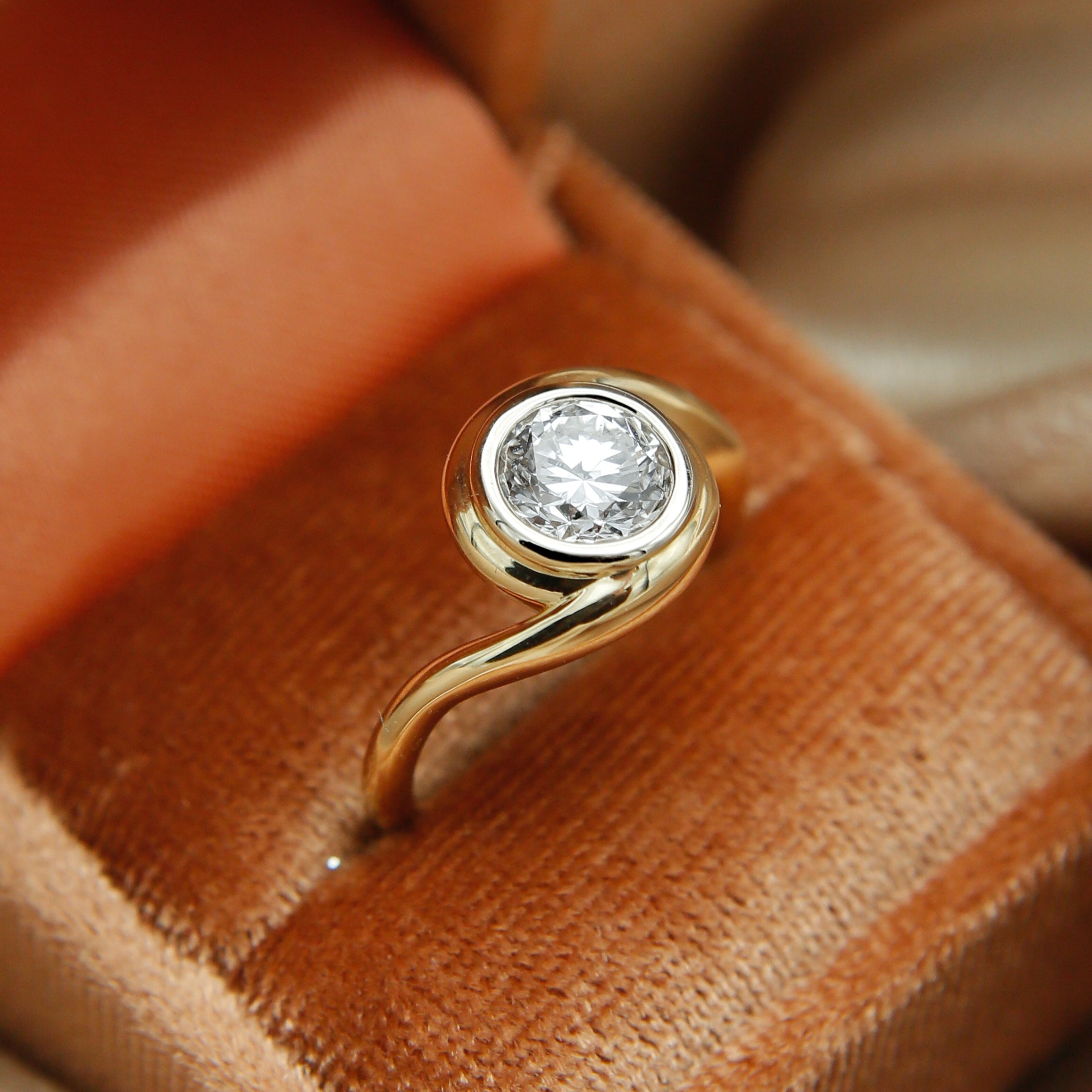 Gold ring with a diamond in a brown jewelry box