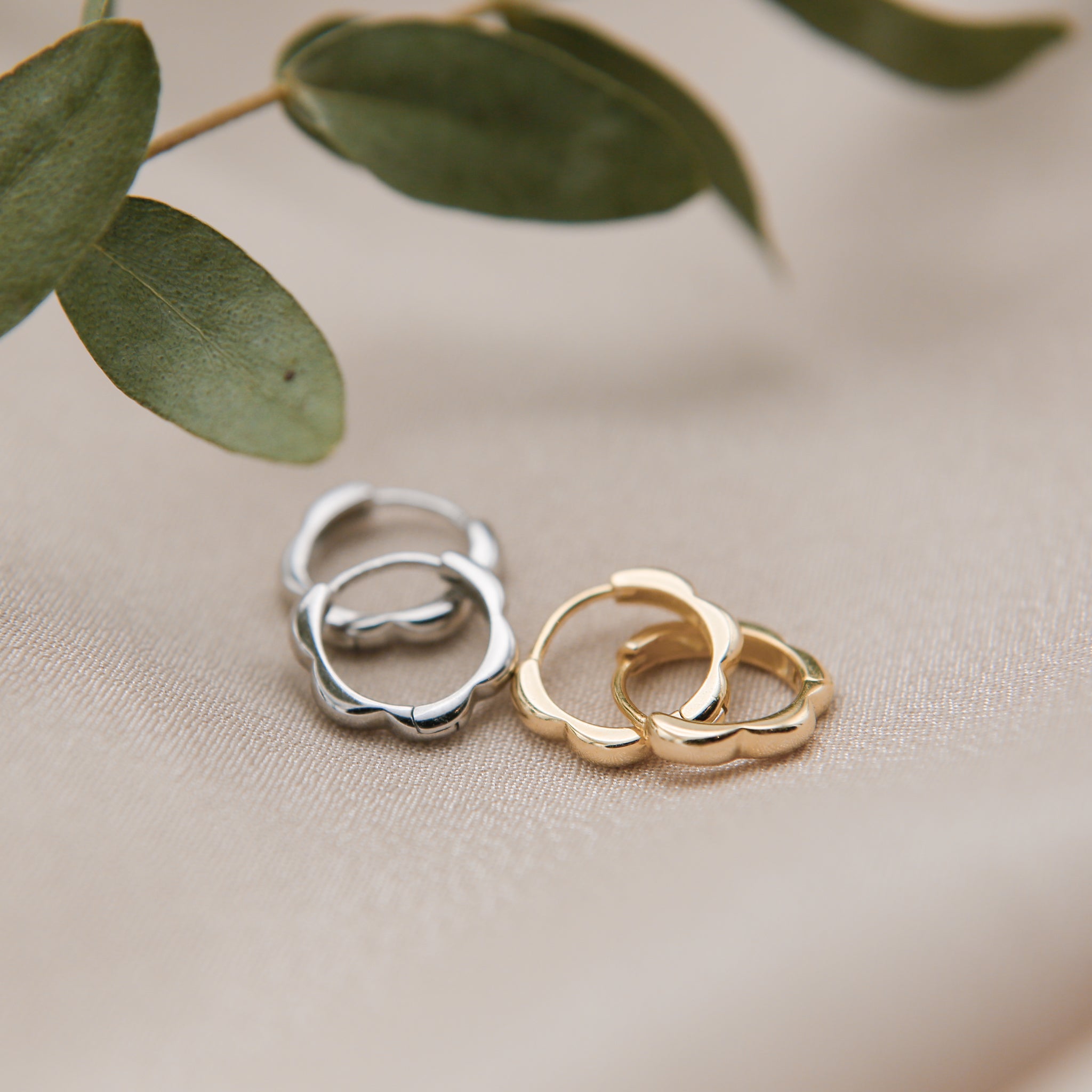 close up of lulu hoops in sterling silver and gold vermiel. petal shaped design huggie hoops