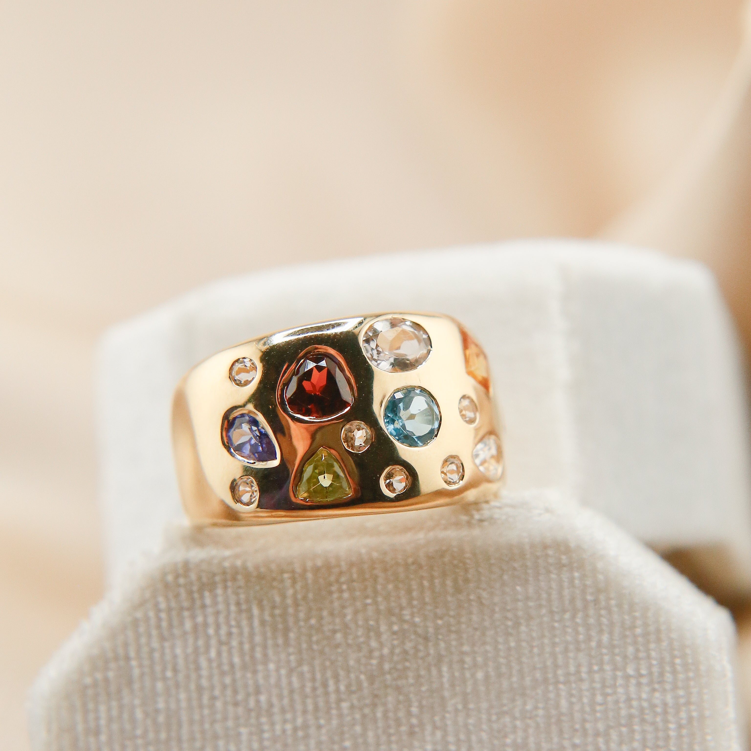 14k gold ring with a wide variety of colorful gemstones all flush set with the wide band. The gemstones are set to look like confetti