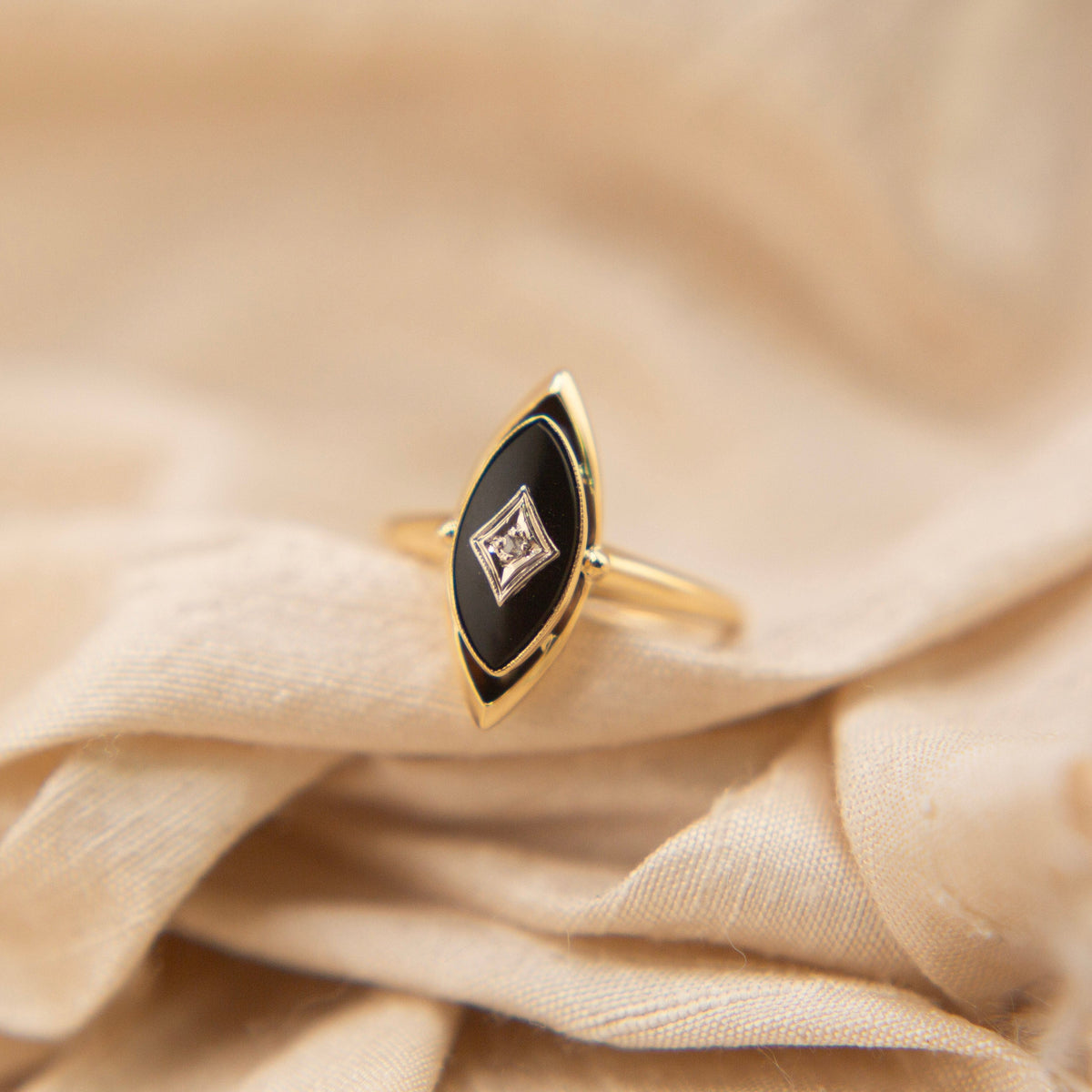 10k Yellow Gold vintage onyx ring with a melee diamond. This onyx is a north south marquis shape with detailing at the top and bottom. In a size 5.75 but can be resized with us