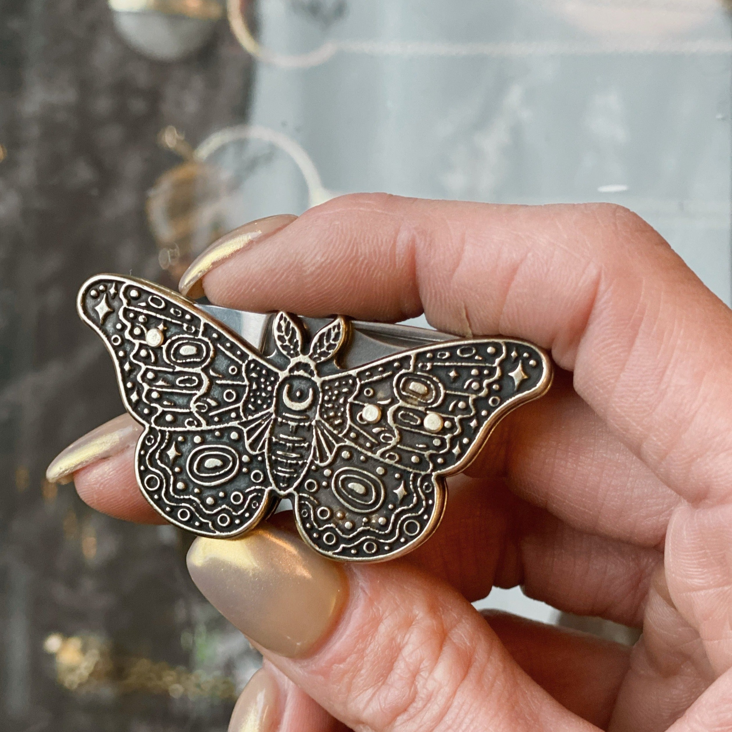 model holding small pocket knife shaped as moth, with dark patina in details