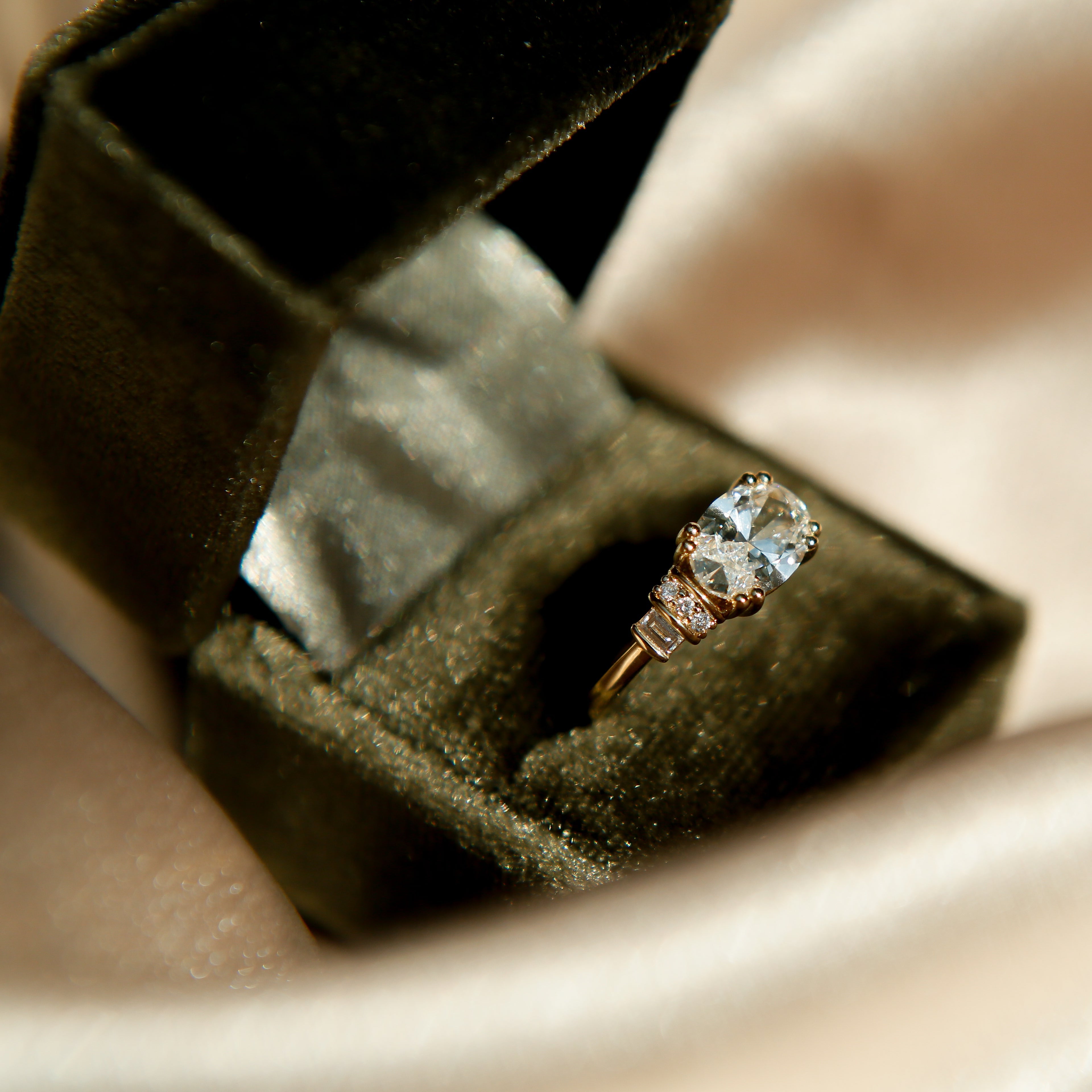 Diamond ring in an open jewelry box on a satin surface