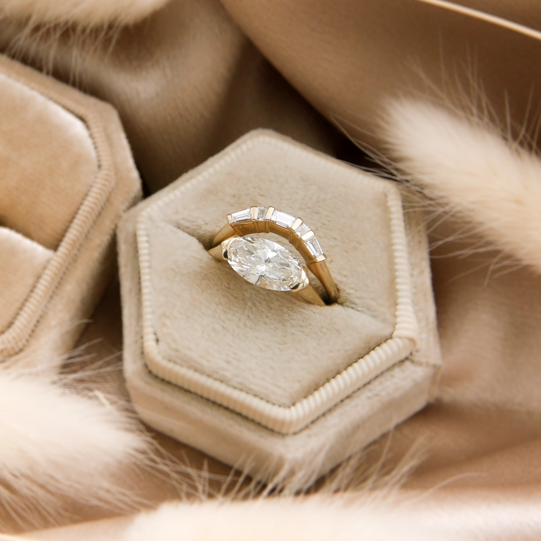 14k yellow gold modern countered wedding band with baguette diamonds paired with east west oval engagement ring