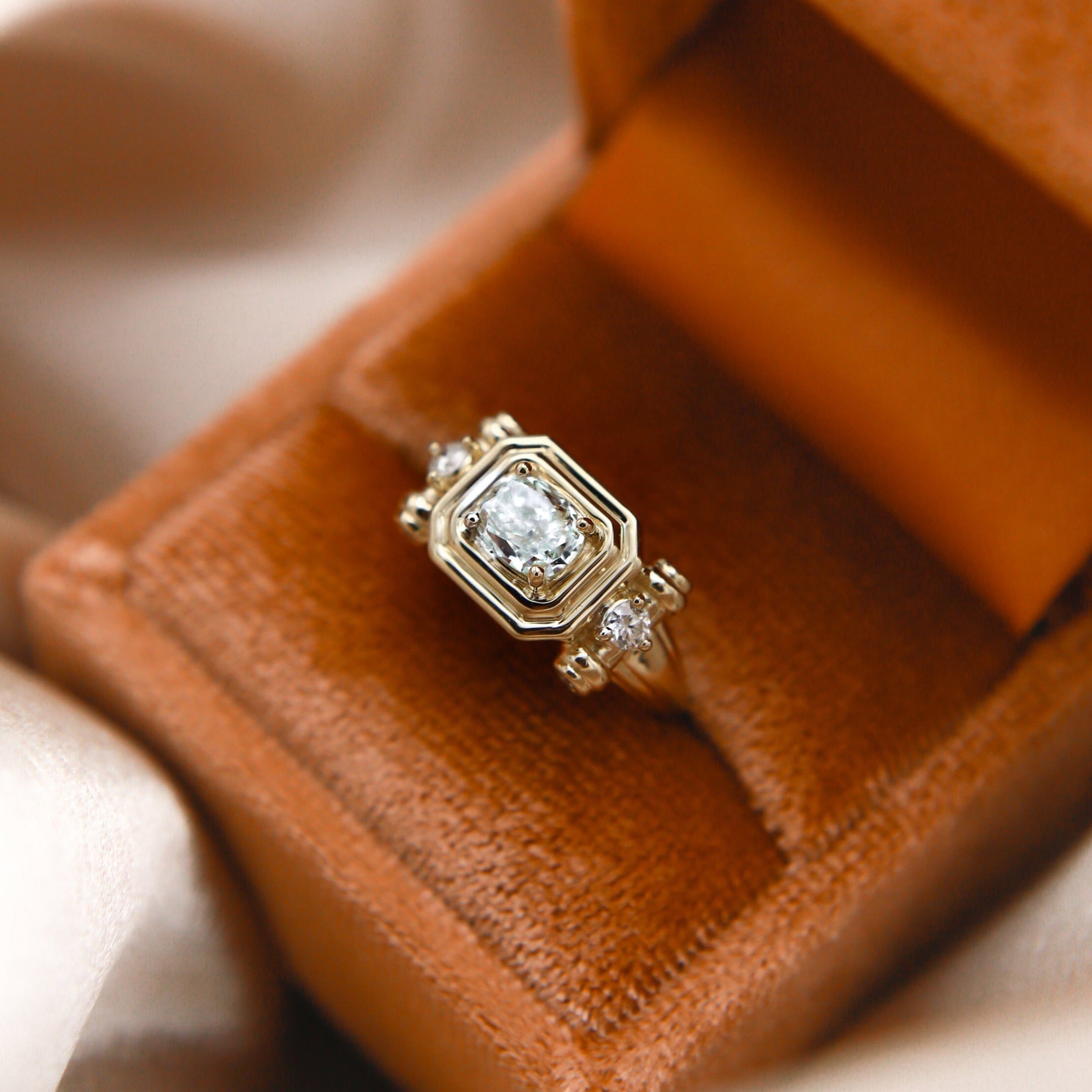 close up of the Diana 14K engagement tank ring, set with 6 adornment. diamonds and 1.5 ct diamond at its center. 