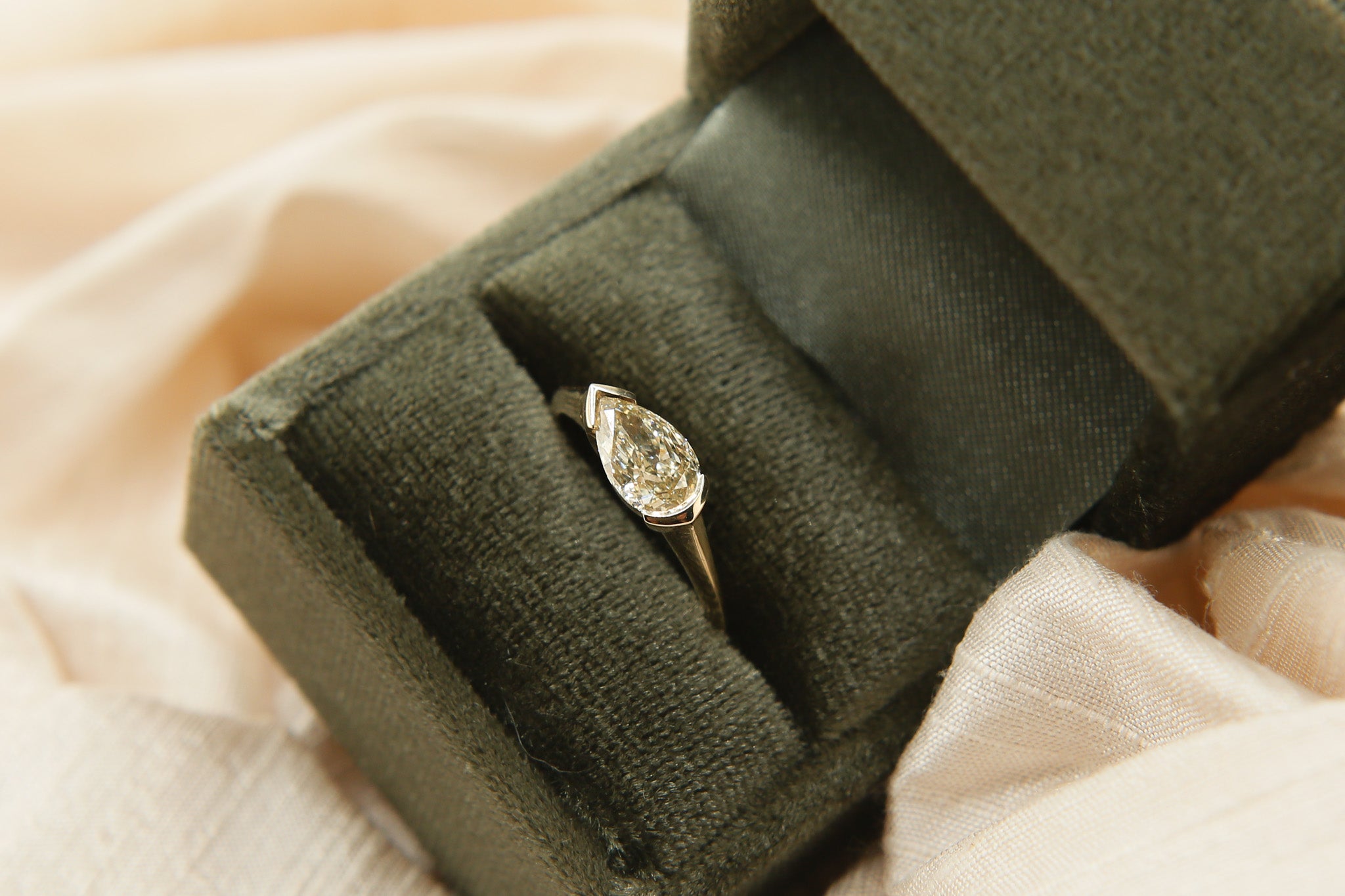 Diamond ring in a green velvet box on a soft fabric background