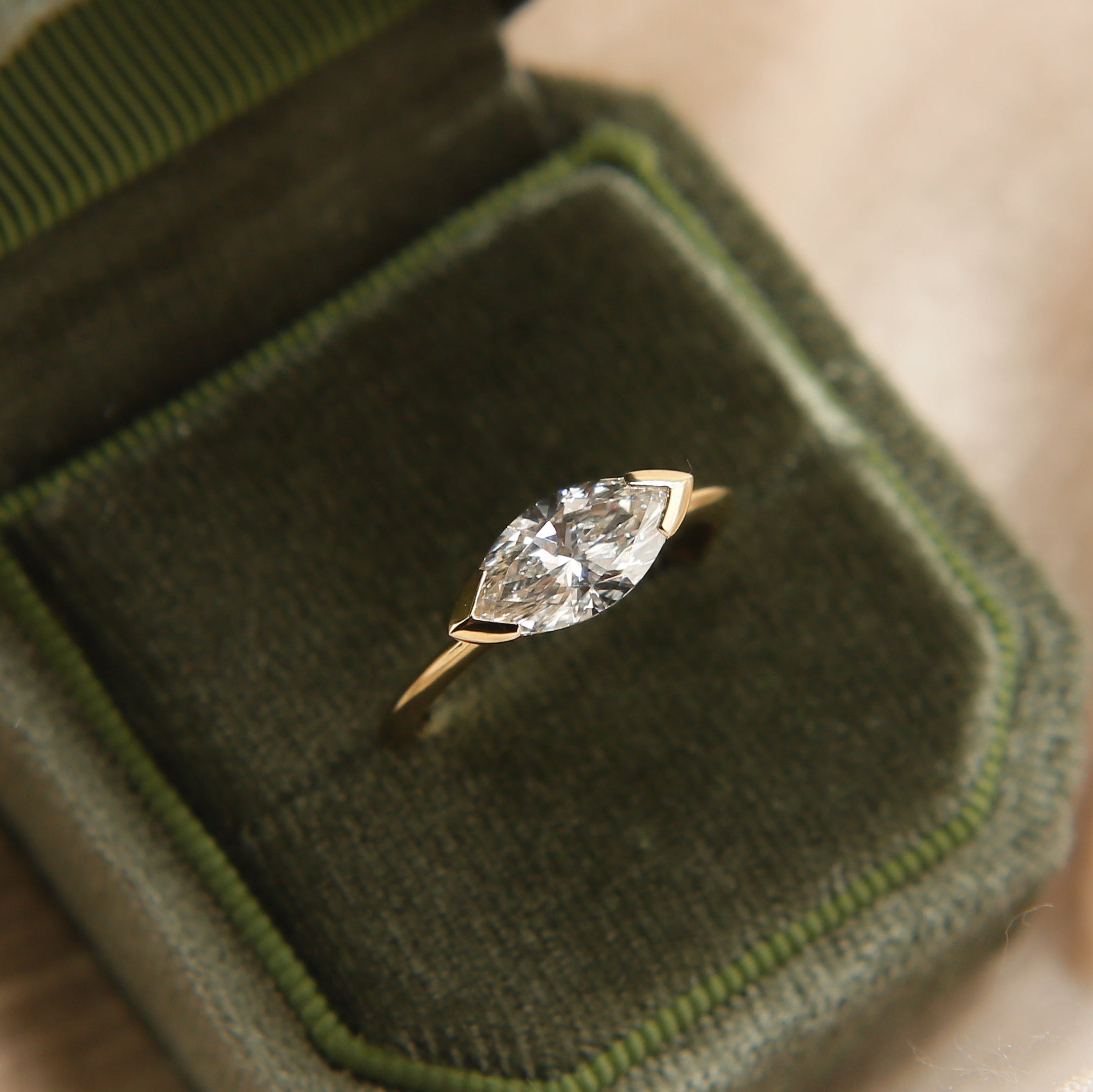 Diamond ring in a green velvet box held by a hand