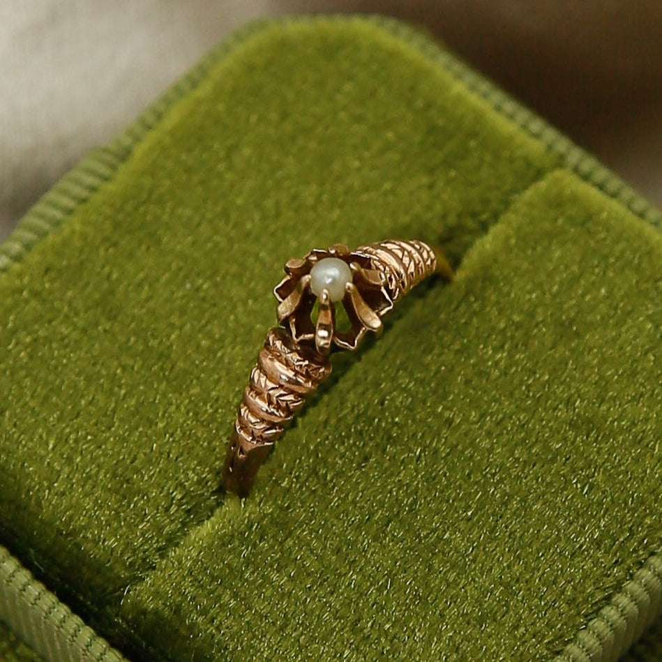 Green velvet ring box with a ring on beige fabric