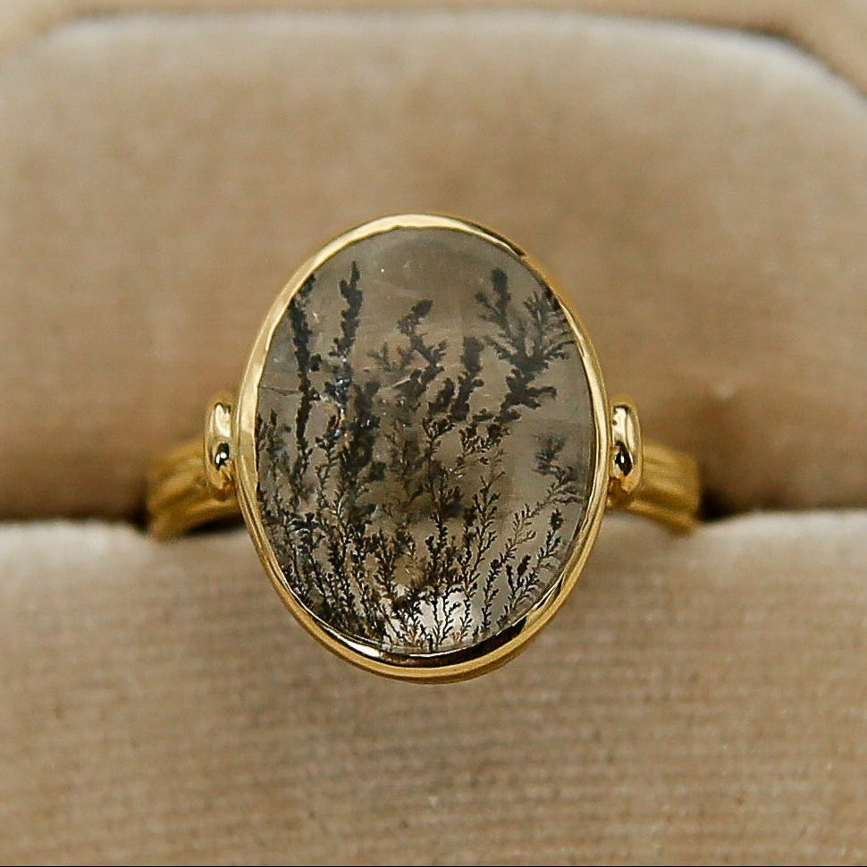Gold ring with a stone on a beige velvet cushion