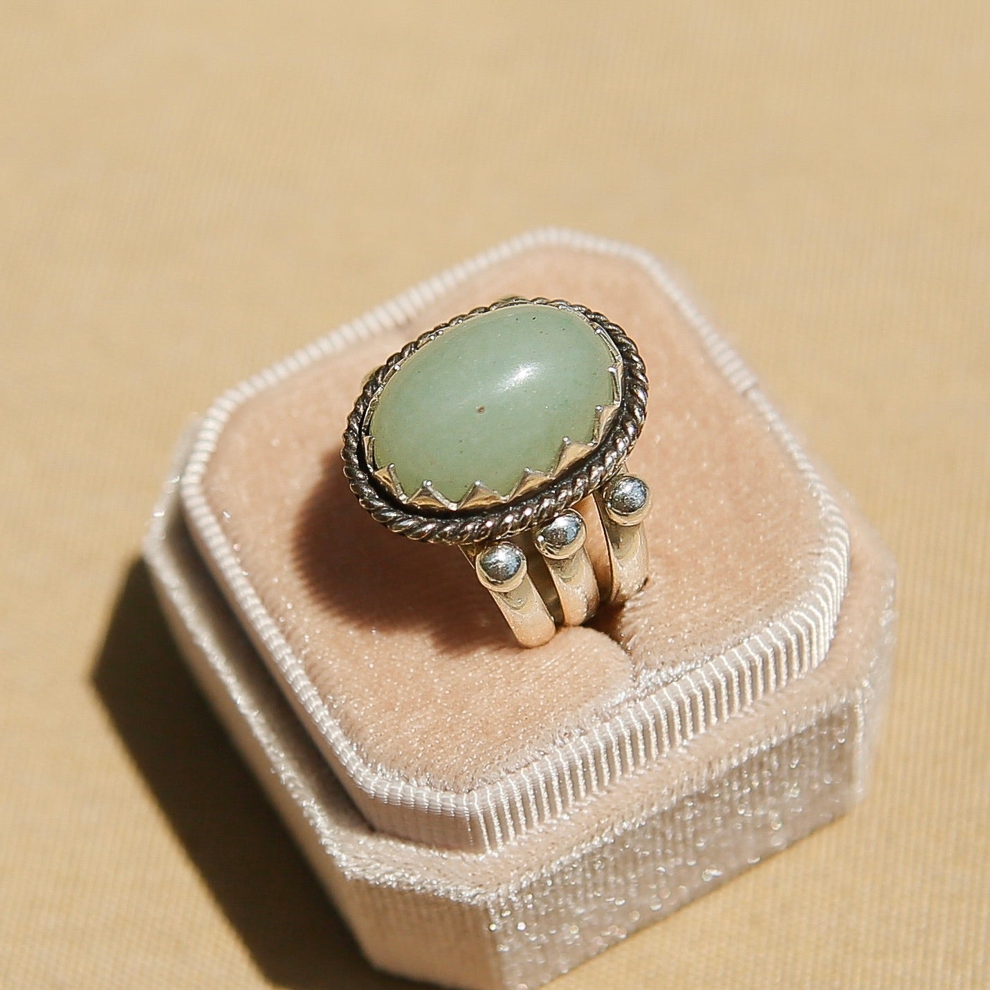 Sterling silver 3 band ring with a light green oval stone. This ring has a bezel like setting made of sharp edges and a rope frame that has been patinated. Sold by Cival Collective in Milwaukee Wisconsin. 