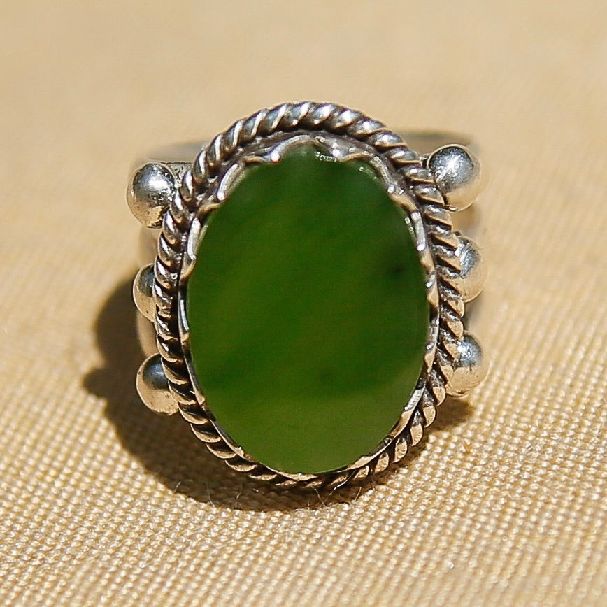 Sterling silver 3 band ring with a flat green oval stone. This ring has a bezel like setting made of sharp edges and a rope frame that has been patinated. Sold by Cival Collective in Milwaukee Wisconsin. 