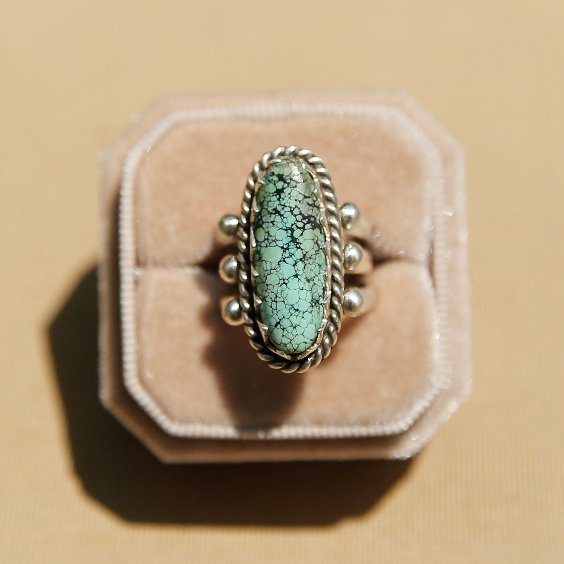 Sterling silver 3 band ring with a long oval turquoise stone. This ring has a bezel like setting made of sharp edges and a rope frame that has been patinated. Sold by Cival Collective in Milwaukee Wisconsin. 