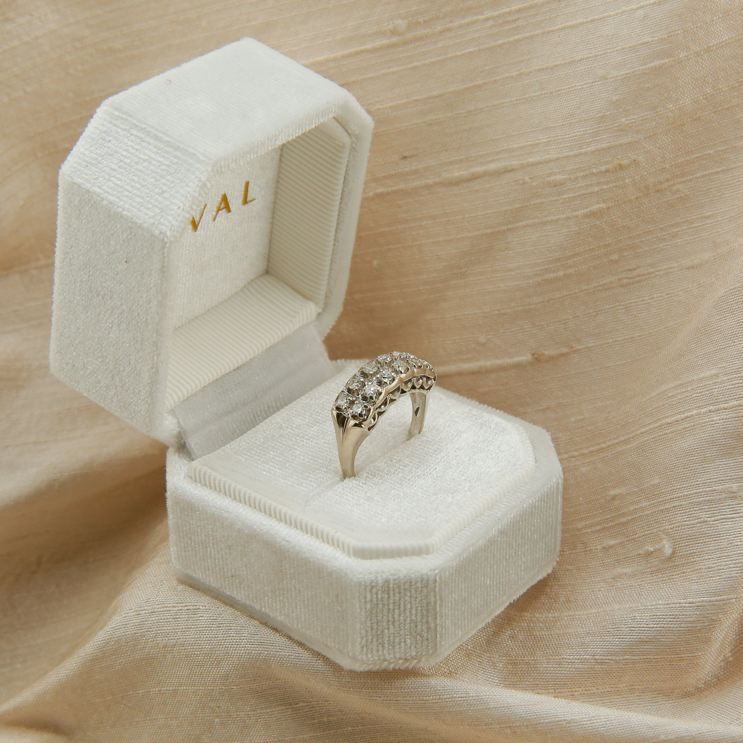 Gold ring in an open jewelry box on beige fabric