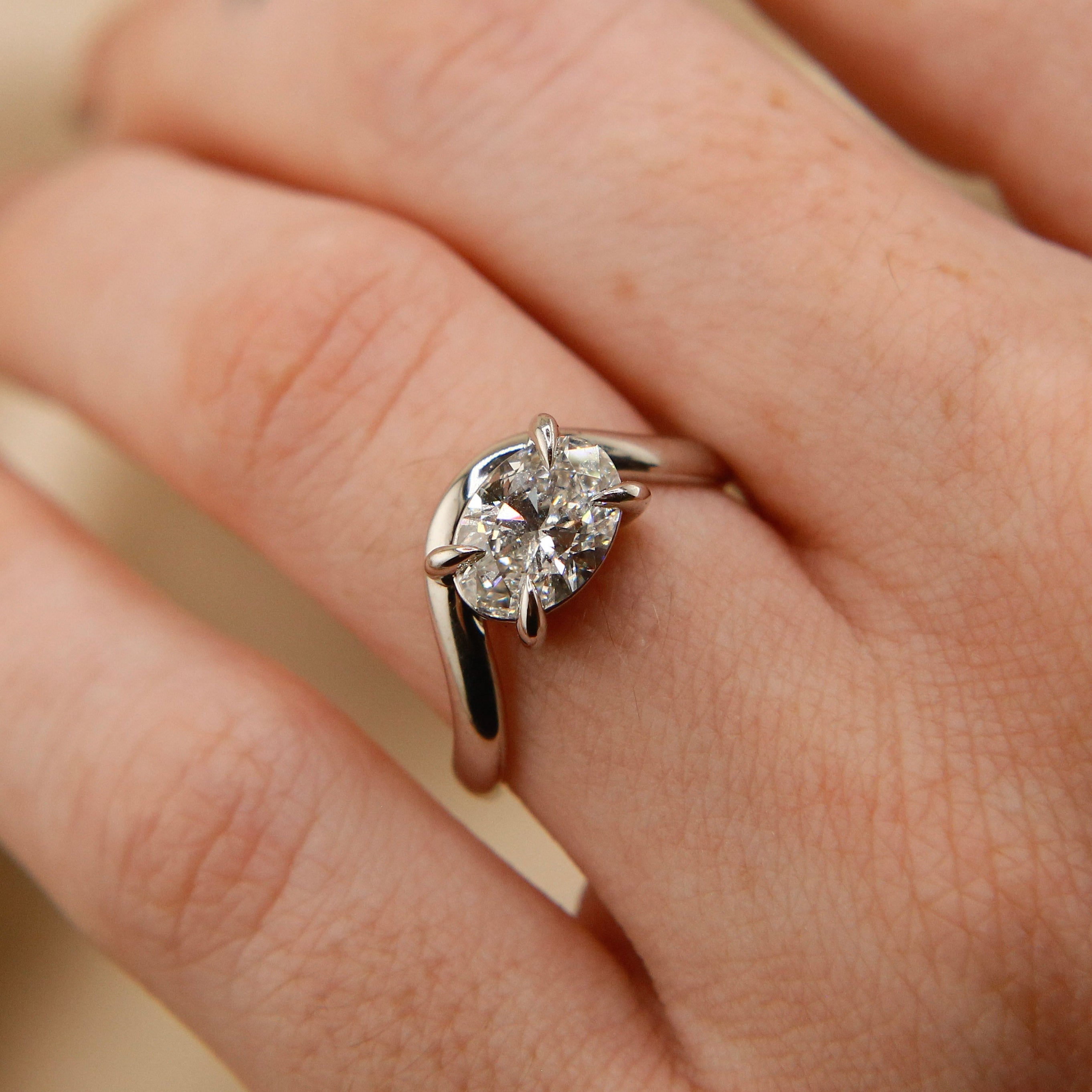 14k white gold oval east west diamond wave engagement ring with claw prongs. Customize this unique ring with your choice of stone type, stone shape and stone size. Diamond, moissanite, round, oval, princess, cushion, asscher, marquise. Cival in Milwaukee Wisconsin. 