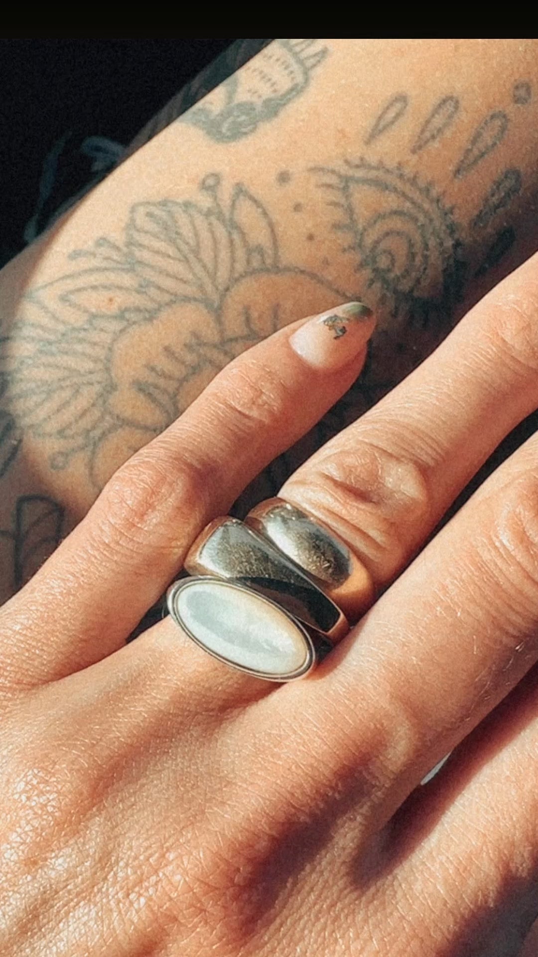 Video of sterling silver dome ring with cloudy white east west facing stone. On hand, stacked with two other chunky rings 