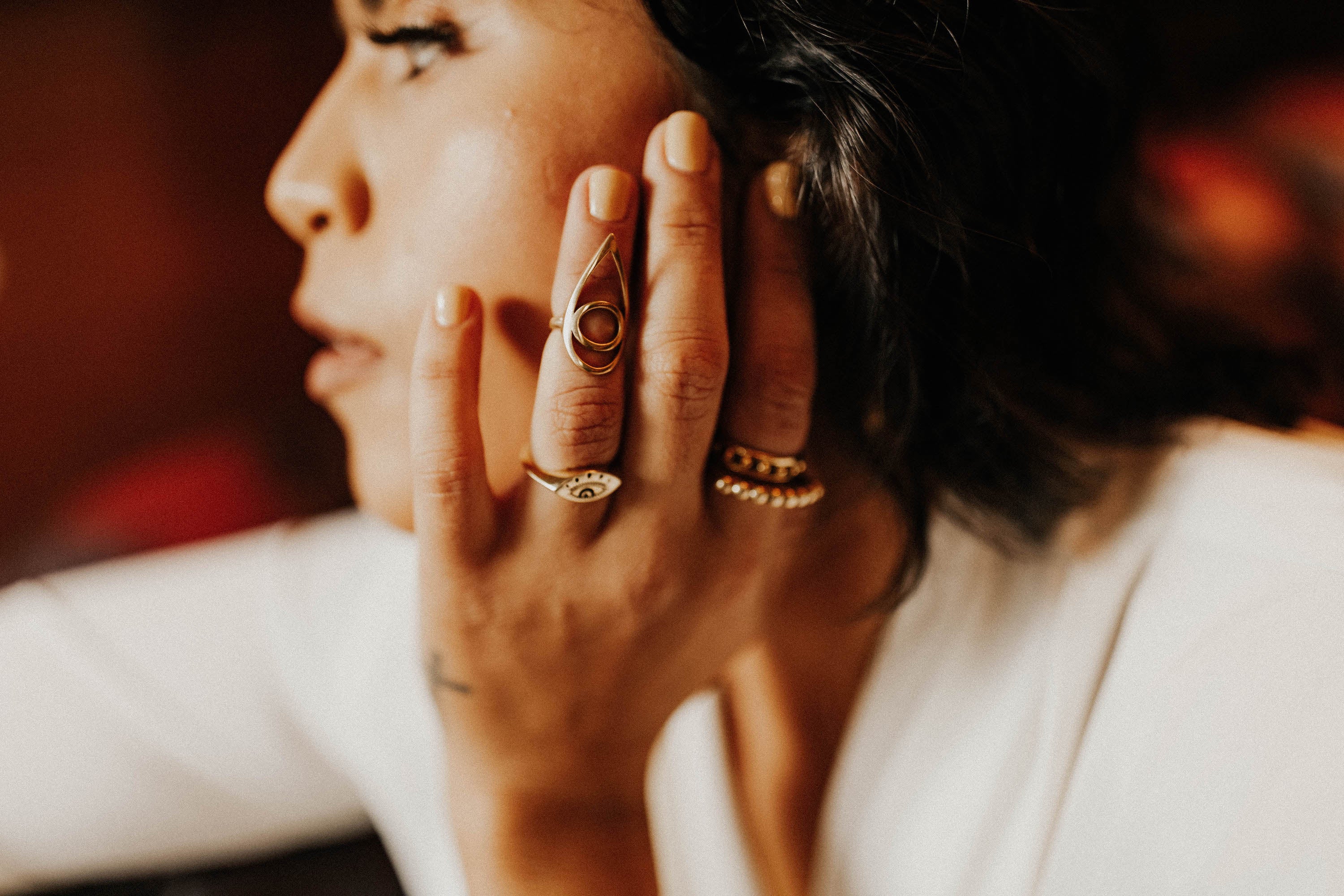 model wearing brass evil eye ring stacked beautifully with other brass rings 