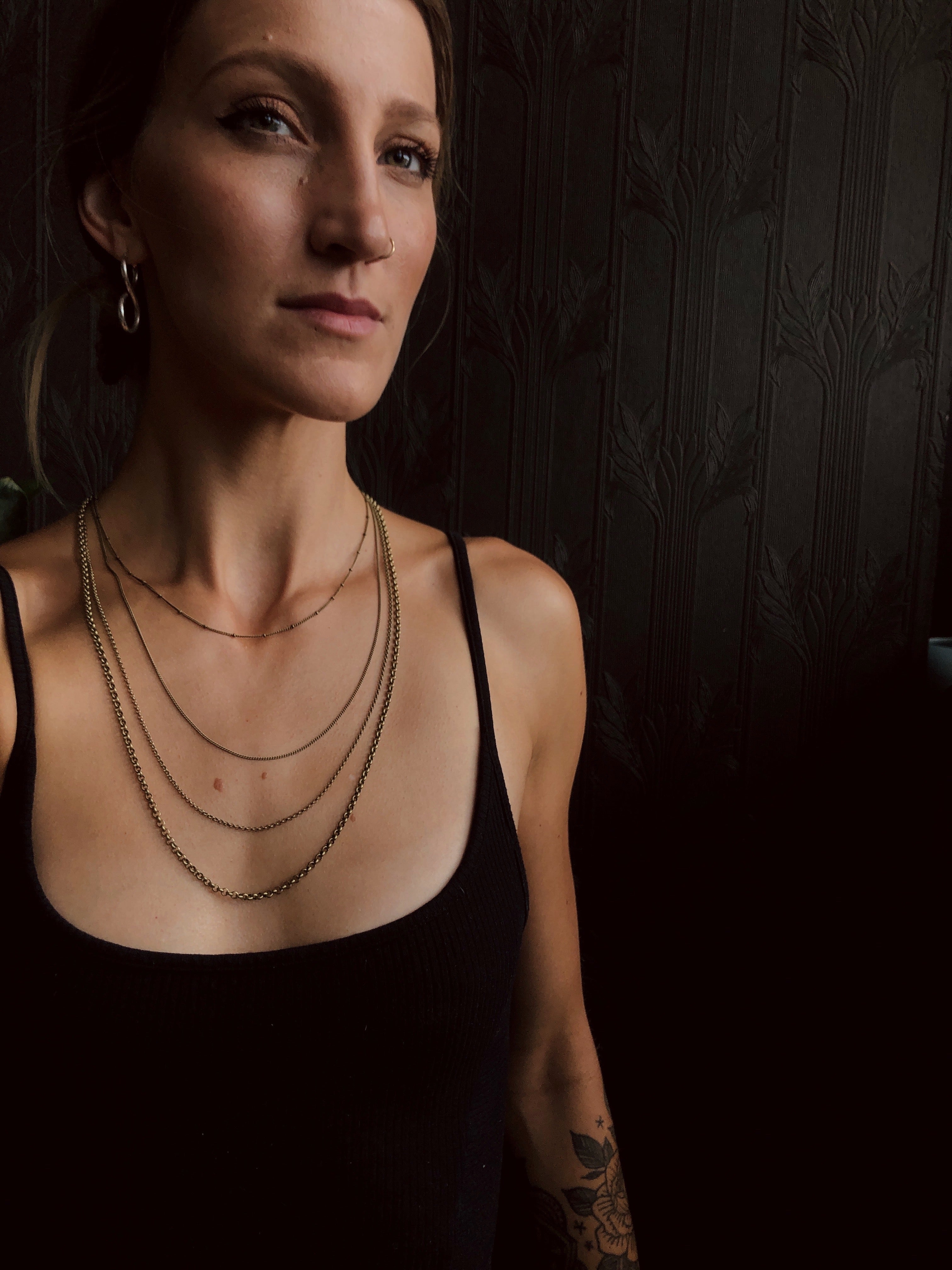 model wearing four brass chains of varying sizes and styles