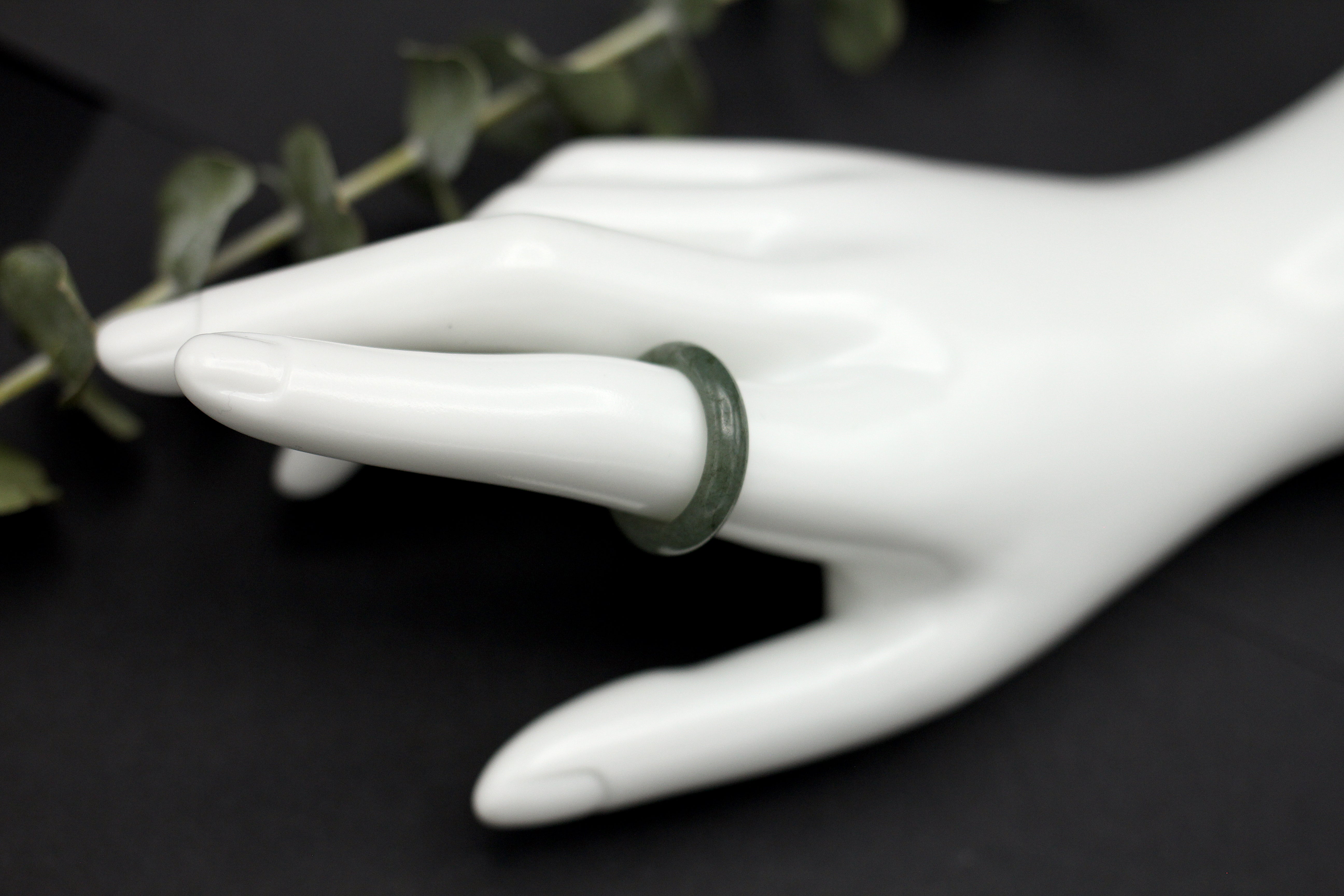Dark jade ring on white hand statue