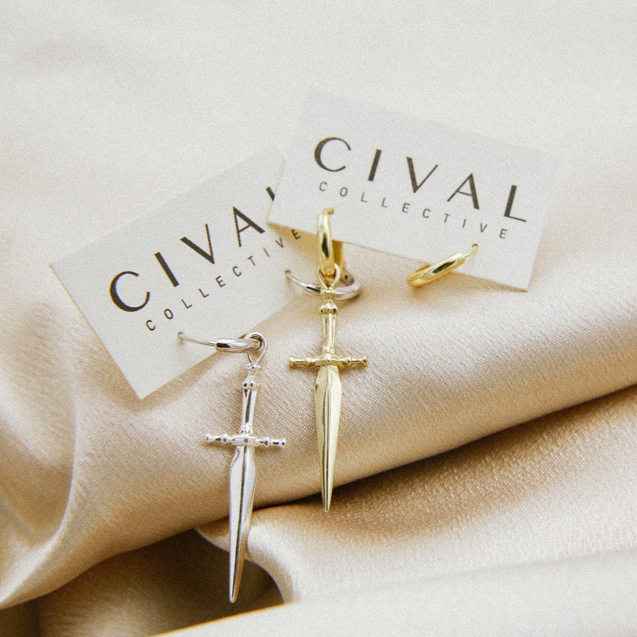 close up of marceline sword earrings in brass and silver. Hoop earrings with a sword pendant featured on the right hoops. 