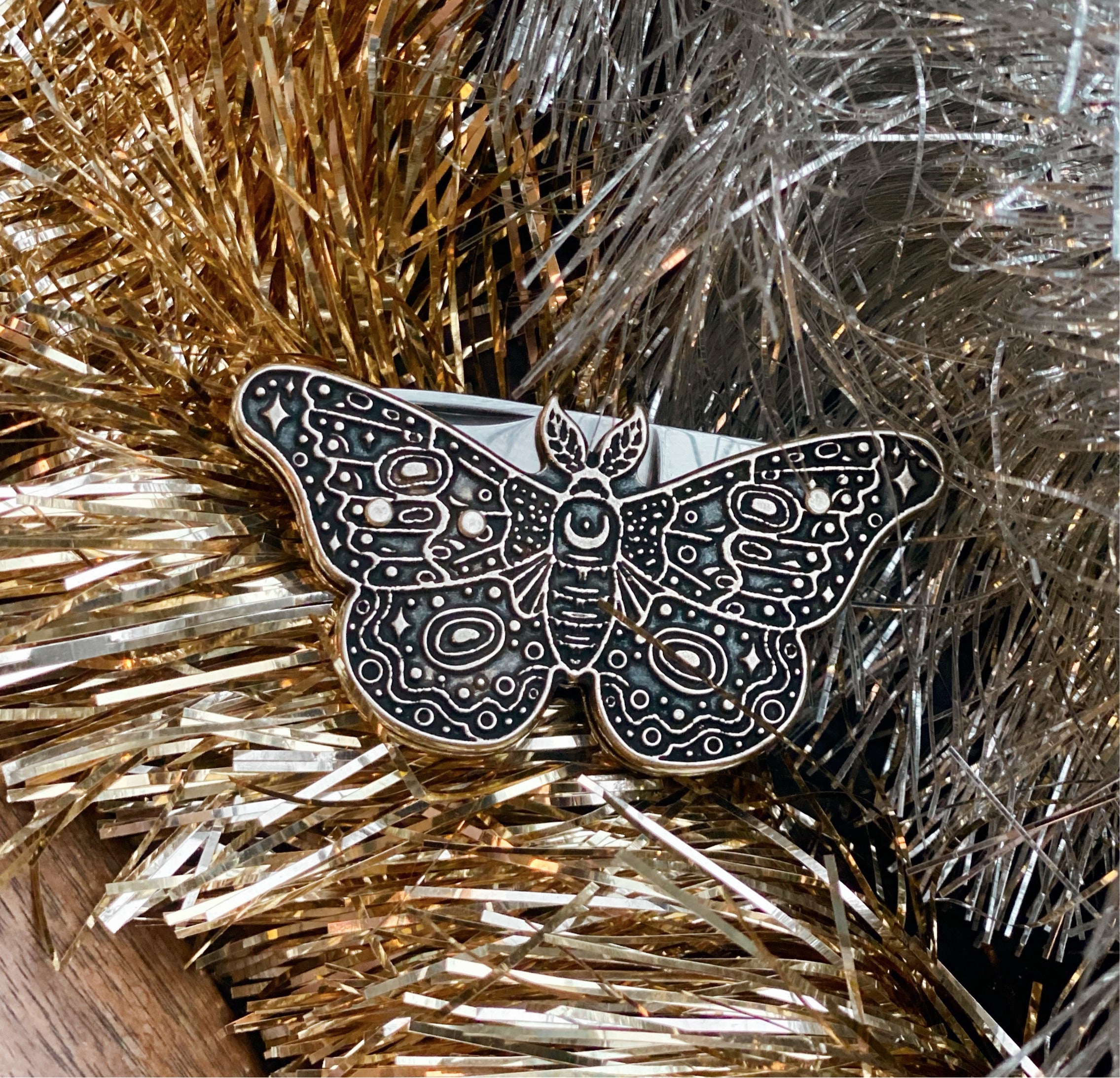 close up of moth pocket knife sitting on gold and silver tinsel